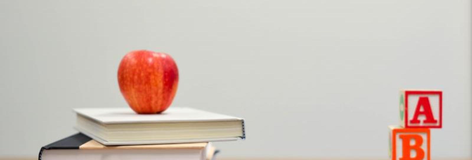 Underviser skrivebord med bøger og æble