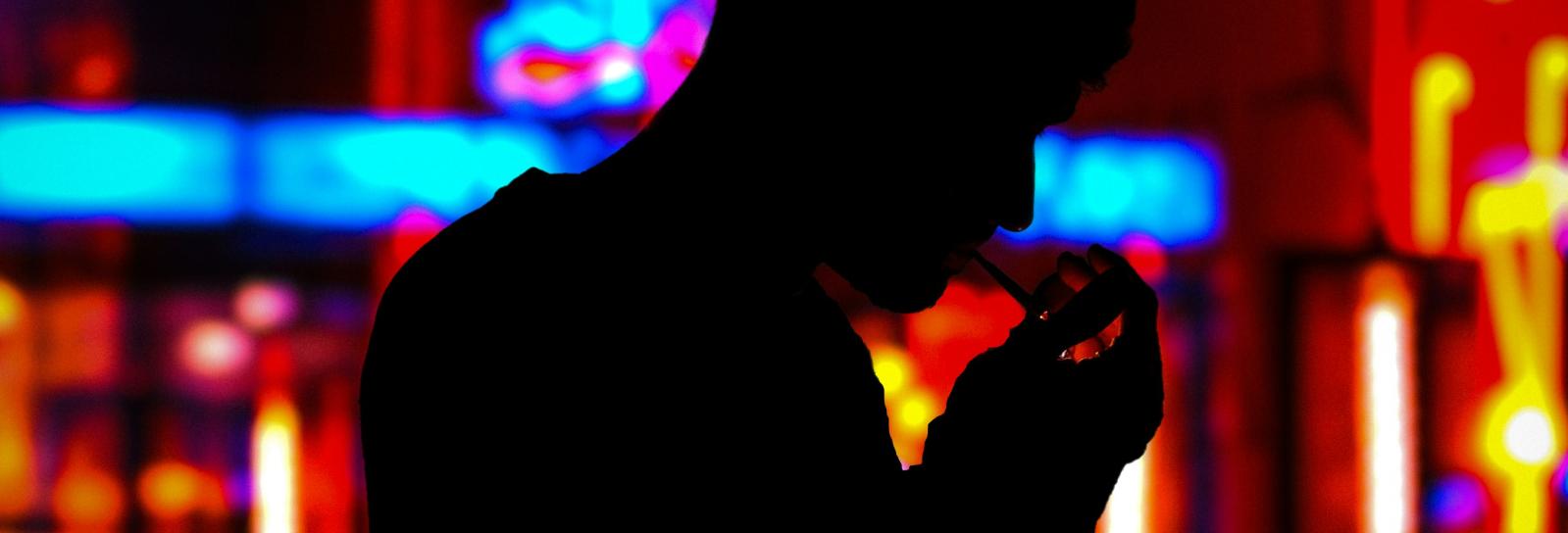 Skyggen af en fyr der tænder en smøg i nattelivet.