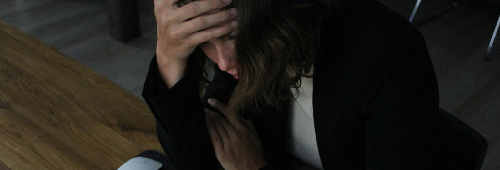 Teenagepige kigger ned i computer, imens hun tager sig til hovedet